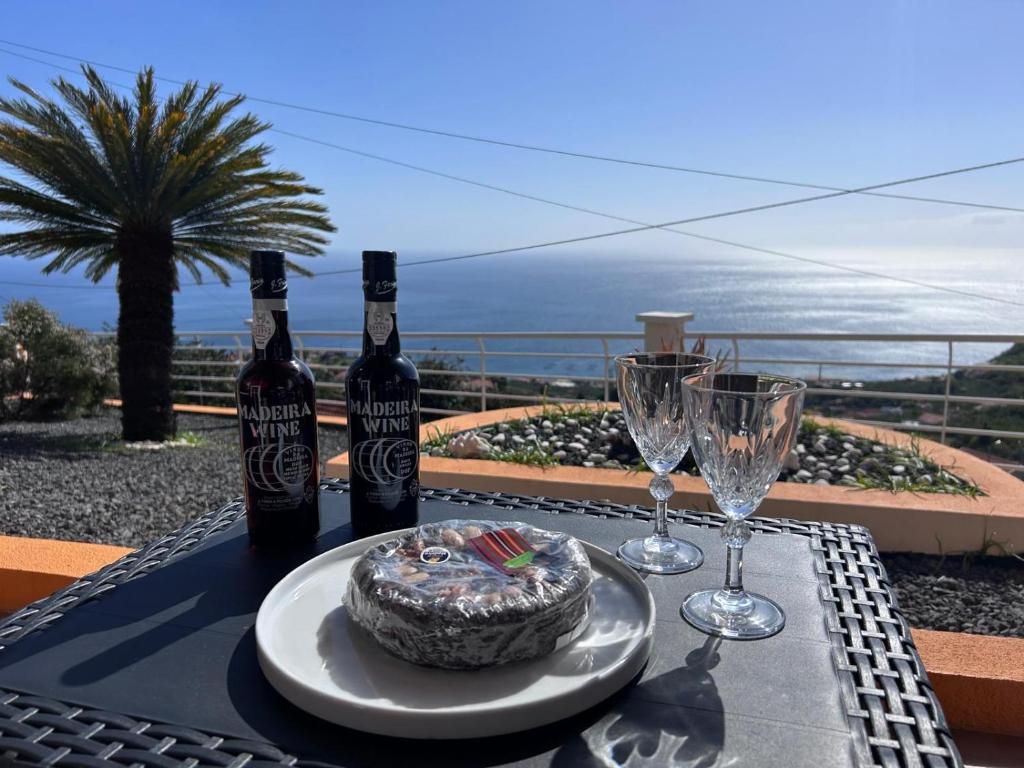 a table with wine bottles and a cake and wine glasses at Vila Mendes - Ocean View in Arco da Calheta