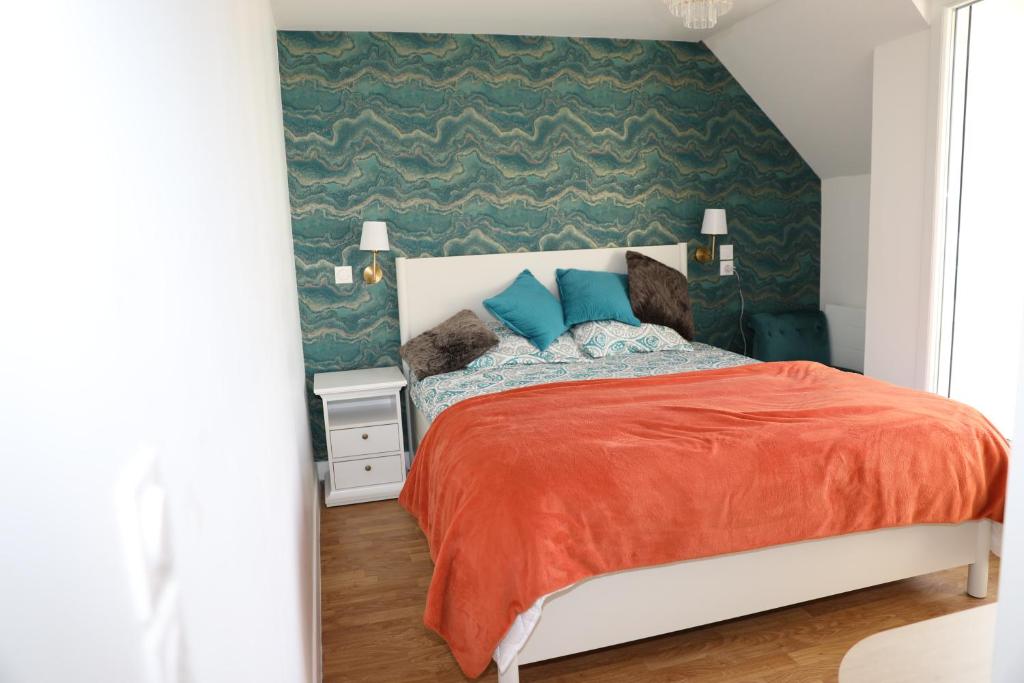 Un dormitorio con una cama con manta naranja y almohadas azules. en Appartement Luxe Floral Stay 15 Min To CDG And Paris, en Le Bourget