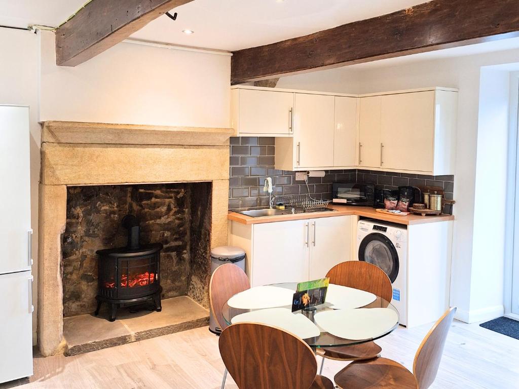 a kitchen with a table and a fireplace at Two-bedroom Cottage - Sandstone Garden Patio - Free Parking - Pets Welcome in Ingrow