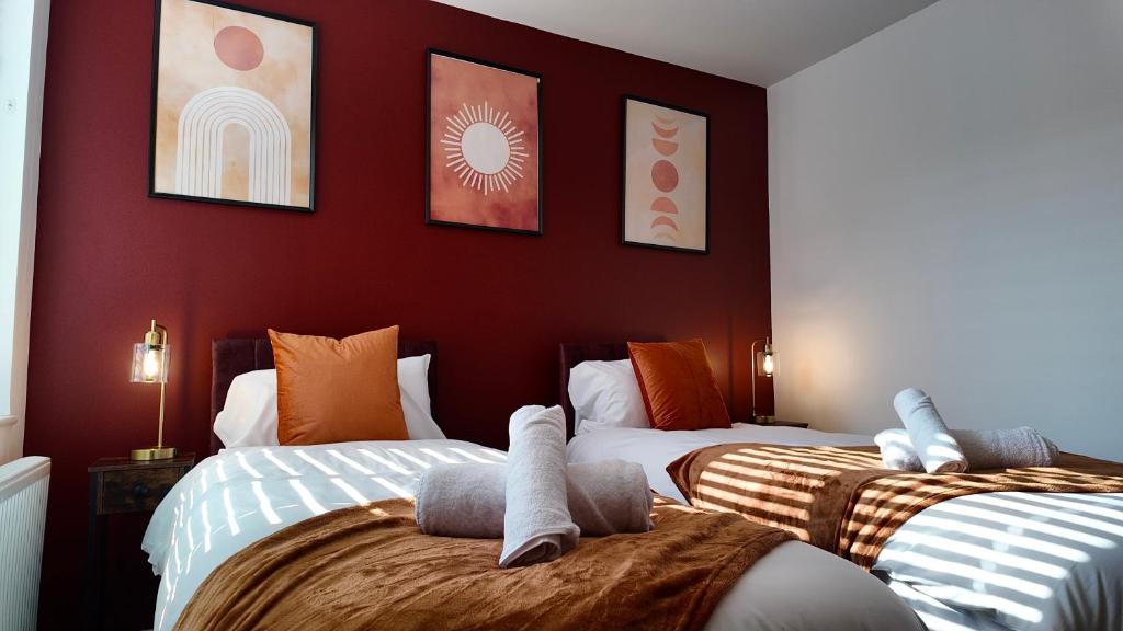 ピーターバラにあるCity Center 1 Bed Flatの赤い壁の部屋にベッドが2つある