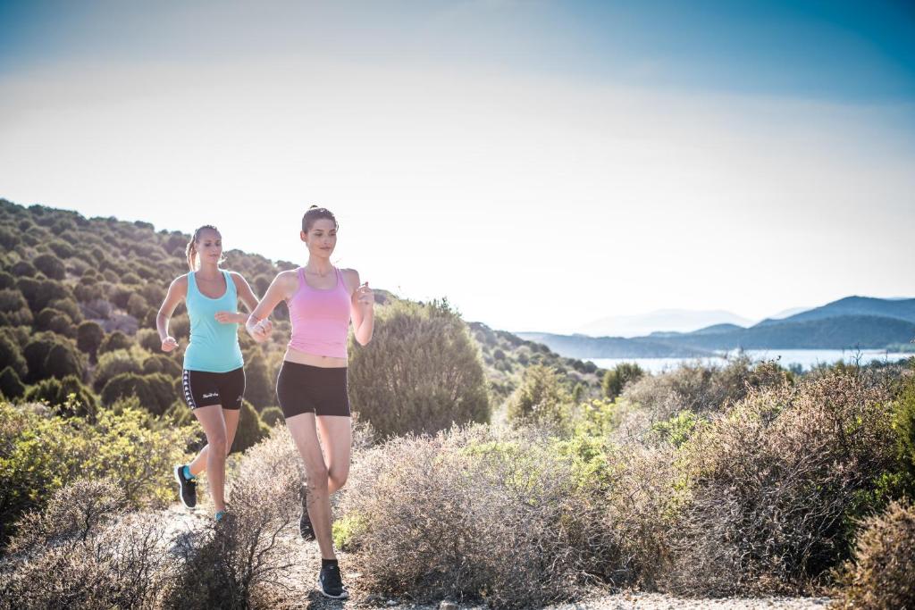 two women running on a trail in the hills at Chia Laguna - Hotel Village in Chia