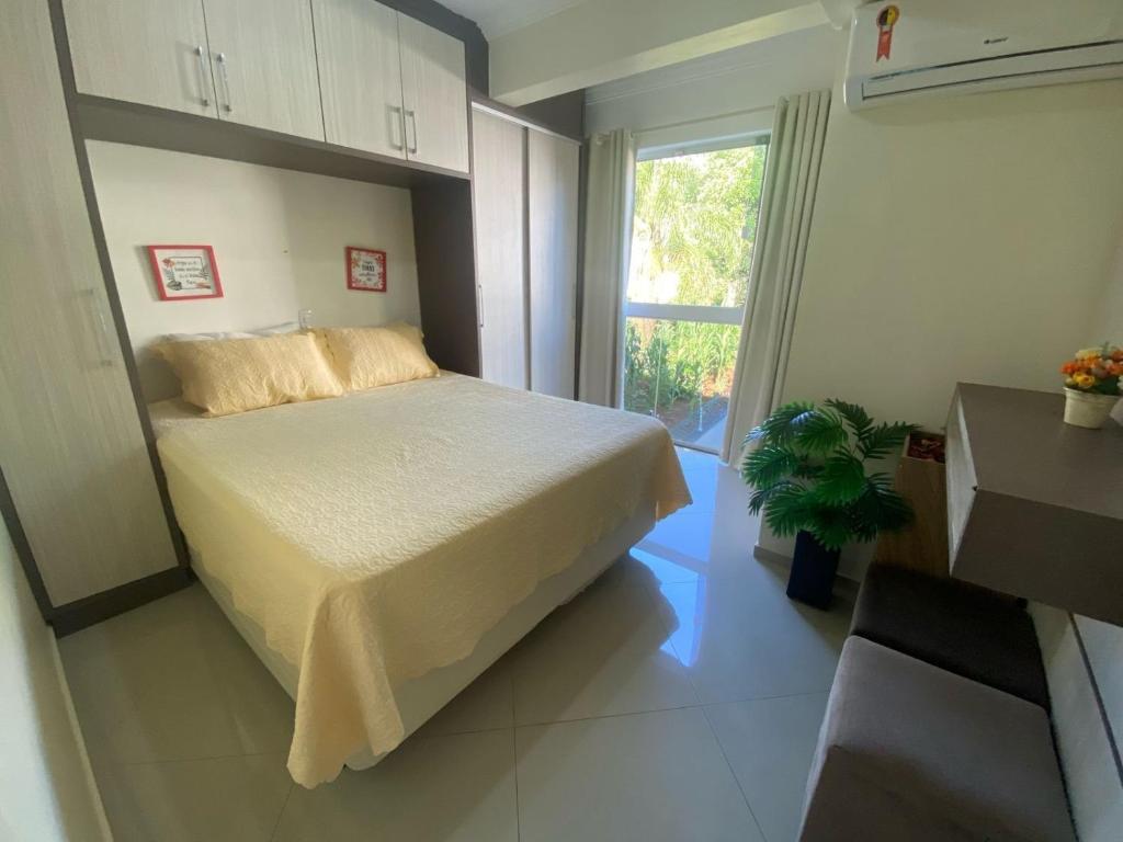 a small bedroom with a bed and a window at Lindo Apto 404 bem localizado Piratuba SC in Piratuba