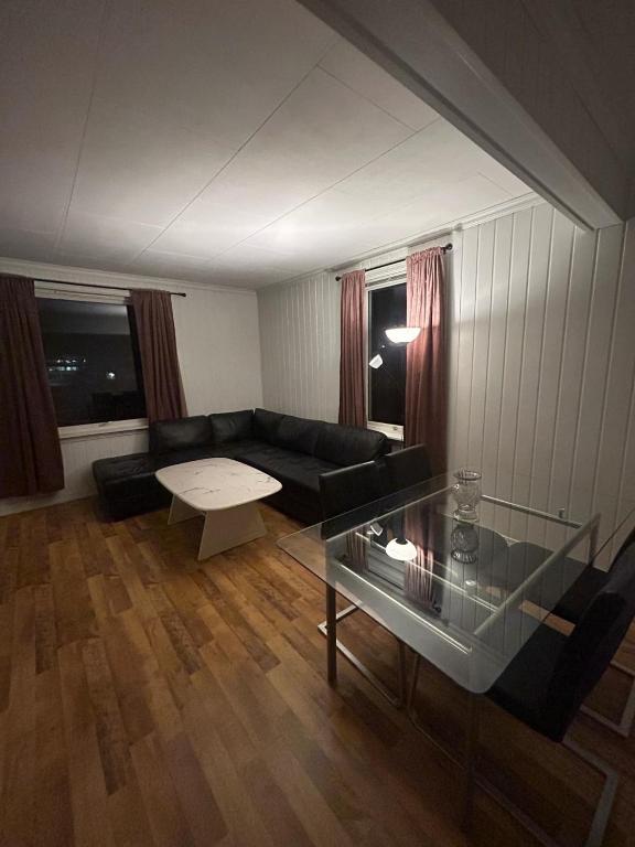 a living room with a black couch and a glass table at Leilighet med 2soverom nær sentrum in Kristiansand