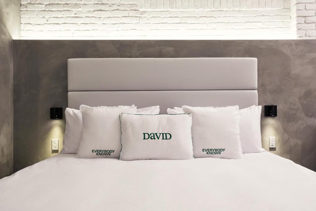 a white bed with pillows with the word david on it at David Hotel in Montréal