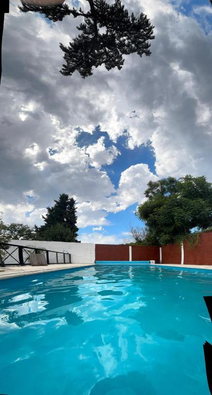 a blue swimming pool with a cloudy sky in the background at Hospedaje en Monte Grande in Monte Grande