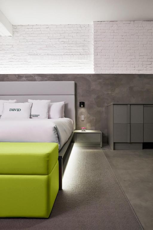 a bedroom with a white bed and a green ottoman at David Hotel in Montréal