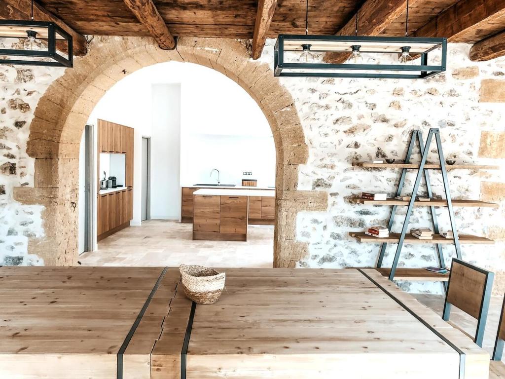a room with a wooden table and a stone wall at Les Rives du Parc Piscine 12 personnes in Lédenon