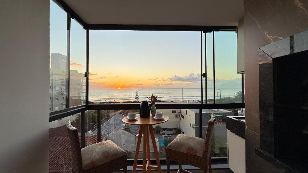 a room with a table and chairs and a large window at IA02- 2 Quartos| Centro| Vista Mar| Churrasqueira in Itapoa
