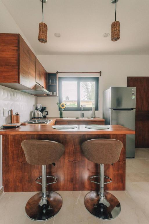 a kitchen with two bar stools and a refrigerator at Beautiful Loft near the Beach in Playa del Carmen