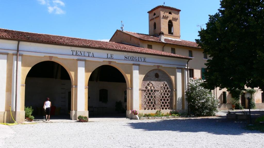 un hombre parado frente a un edificio con una torre en Tenuta Le Sorgive Agriturismo, en Solferino