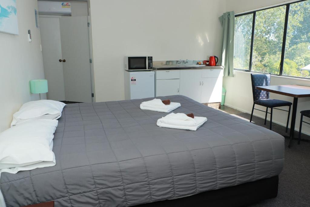 a bedroom with a bed with two towels on it at Drury Motor Lodge in Drury