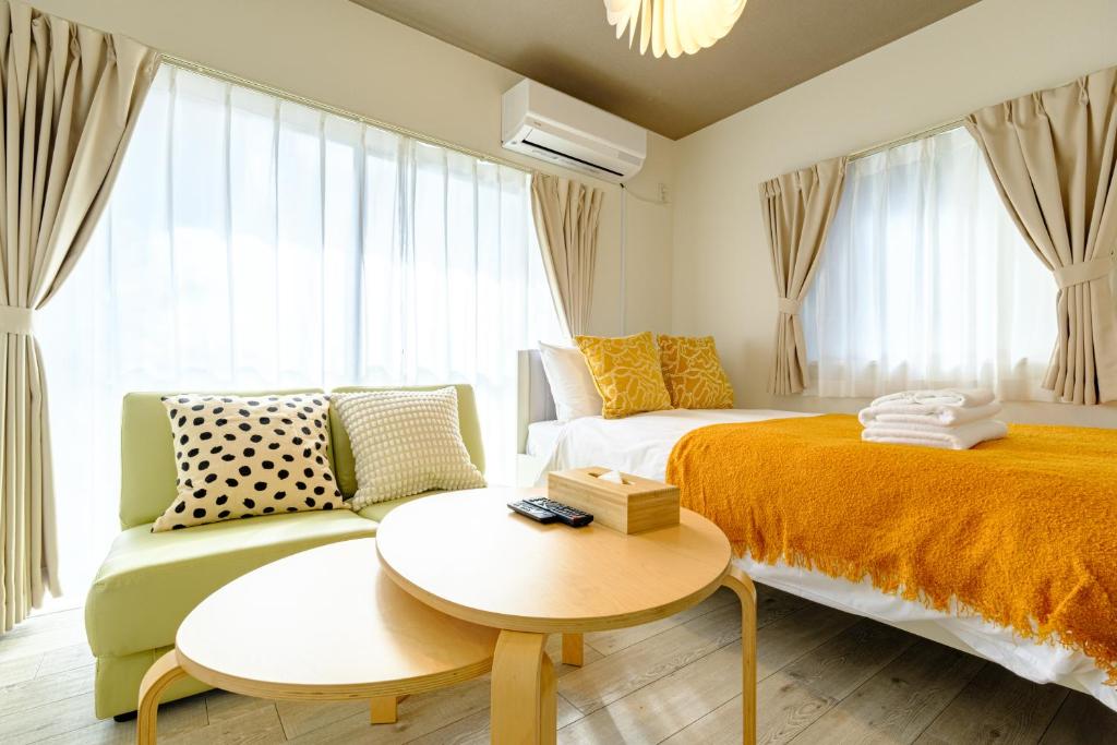 a bedroom with two beds and a couch and a table at CREARE Residence Kagurazaka - クレアーレ神楽坂ゲストハウス105号室 in Tokyo