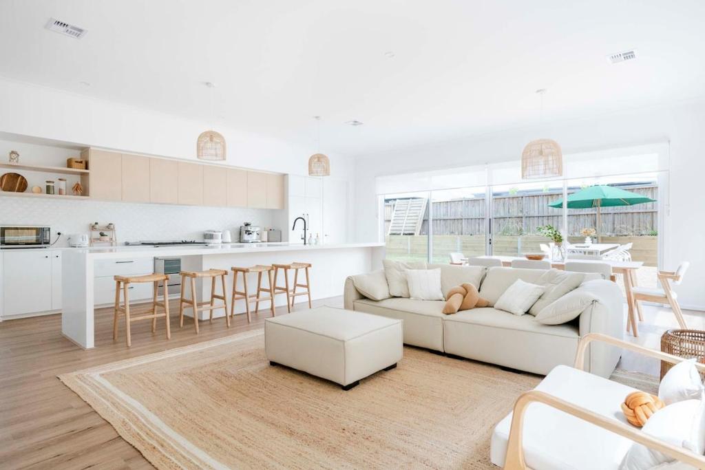a white living room with a white couch and a kitchen at Torquay Beach Getaway in Torquay