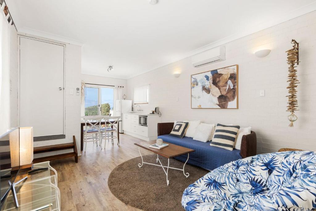 a living room with a blue couch and a table at Quay's Cabin - Absolute Beachfront with Views in Callala Beach