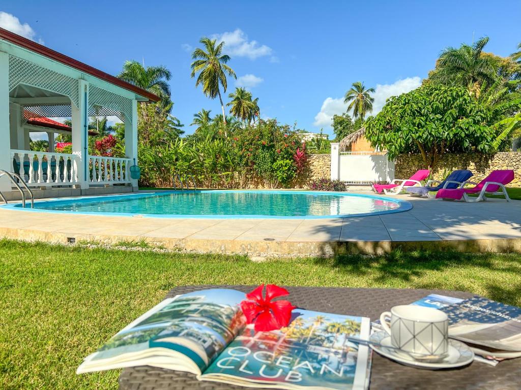 a table with a book next to a swimming pool at Mango house bliss in Las Galeras