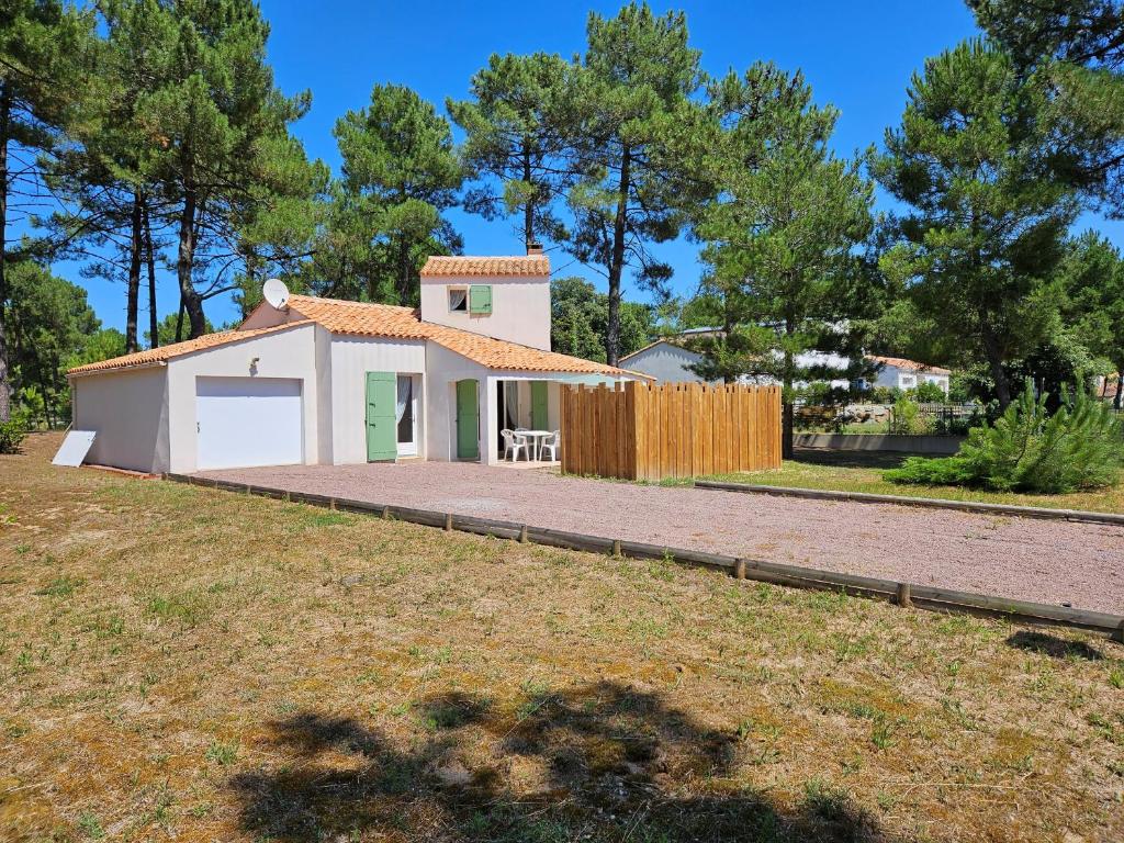 une petite maison blanche avec une clôture dans une cour dans l'établissement Maison 5 pers. proche plage, forêt, et centre bourg à La Faute-sur-Mer, avec jardin et garage - FR-1-476-68, à La Faute-sur-Mer