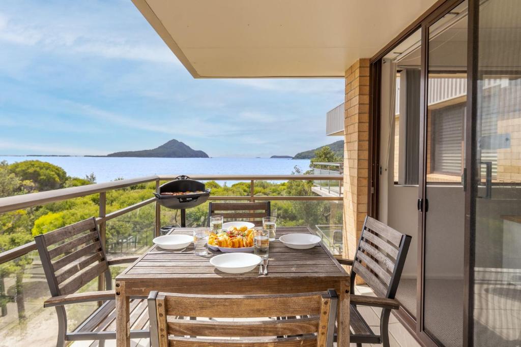 a table on a balcony with a view of the ocean at Intrepid 12 right on the beachfront in Shoal Bay