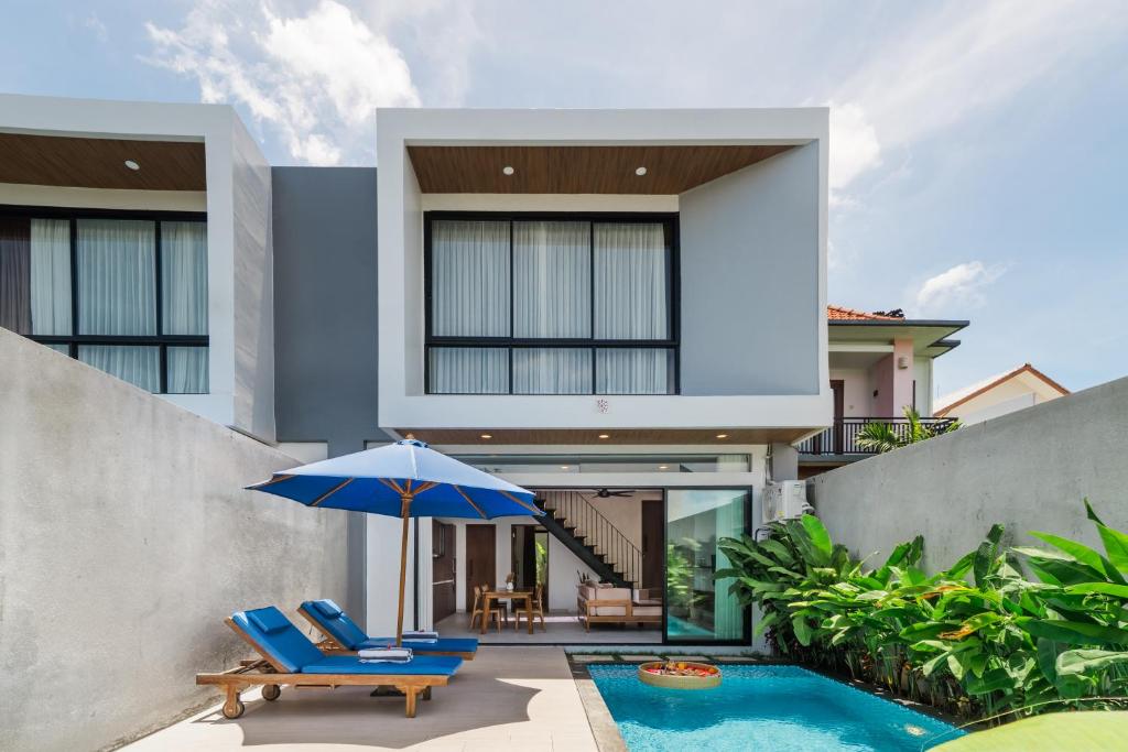 a house with a swimming pool and two chairs and an umbrella at Sanur Bali Villas by Premier Hospitality Asia in Sanur