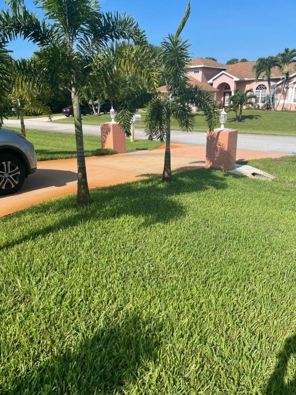 a grassy area with palm trees on a street at Carols Palm in Port Saint Lucie