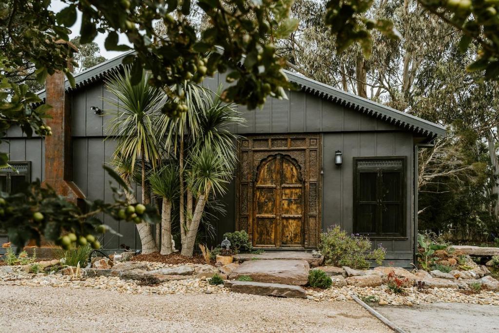 a house with a wooden door and a palm tree at The Temple - Country Farm Retreat in Launching Place