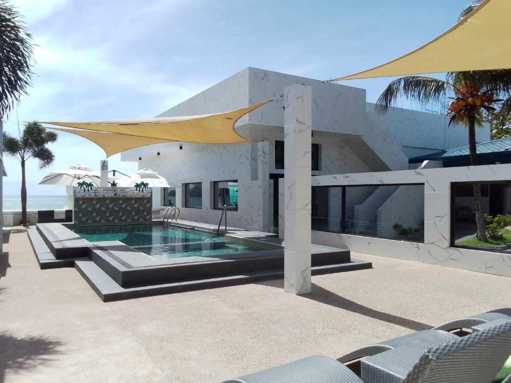 a house with a swimming pool and chairs and the ocean at Cave Beach Resort - Boutique Accomodation in Dingalan