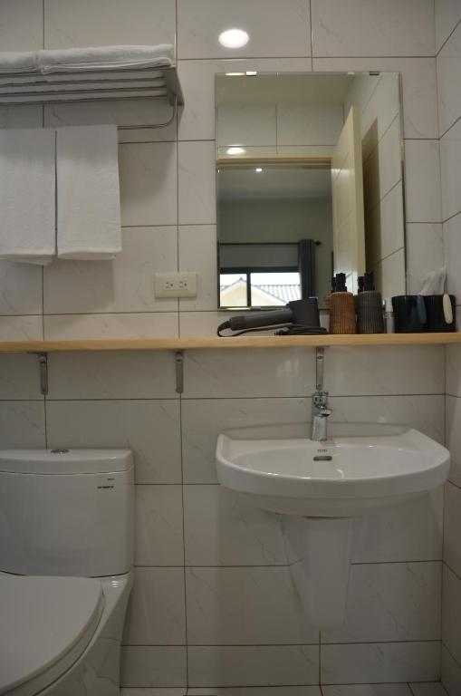 a bathroom with a sink and a toilet and a mirror at Kinmen Fujian Homestay in Tung-chou