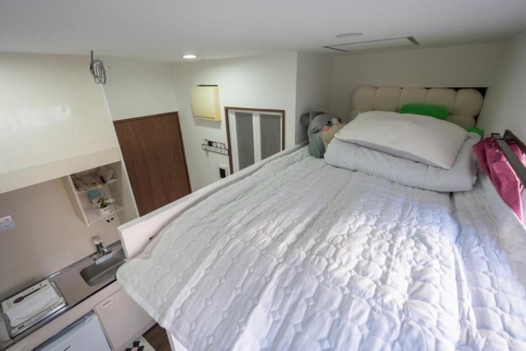 1 cama blanca grande en una habitación pequeña en 王202整套私人卫浴厨房 洗衣机 车站步行5分钟 上野站地铁直达, en Tokio