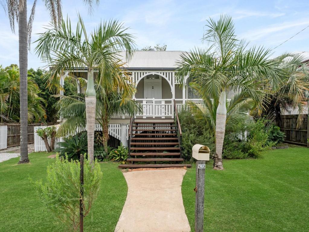 a house with palm trees and a walkway at Silkstone Cottage in Bundamba