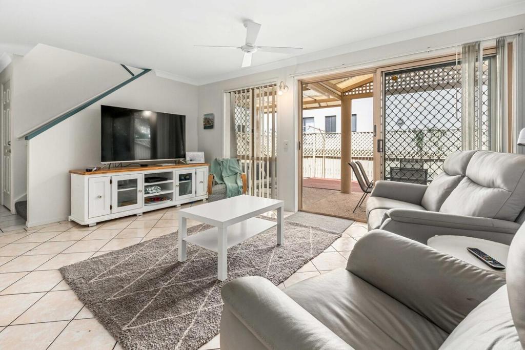 a living room with a couch and a tv at McNaughton Townhouse in Redcliffe