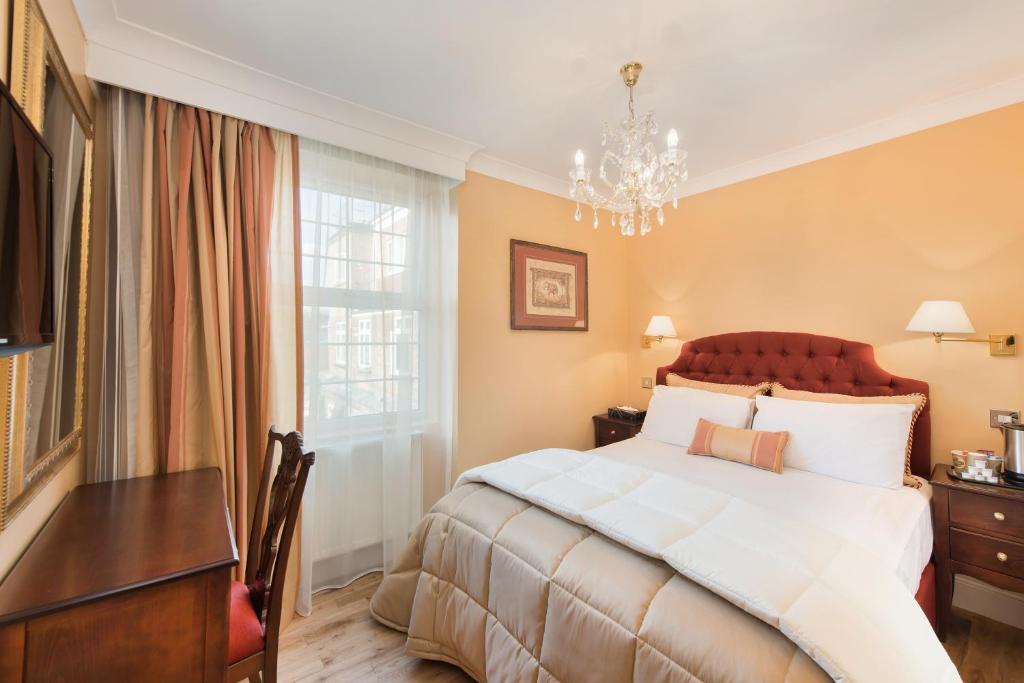 - une chambre avec un grand lit et un lustre dans l'établissement London Residence, à Londres