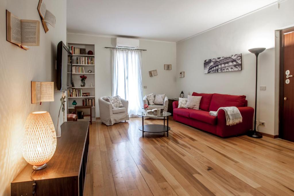 a living room with a red couch and wooden floors at Domus Colosseum in Rome