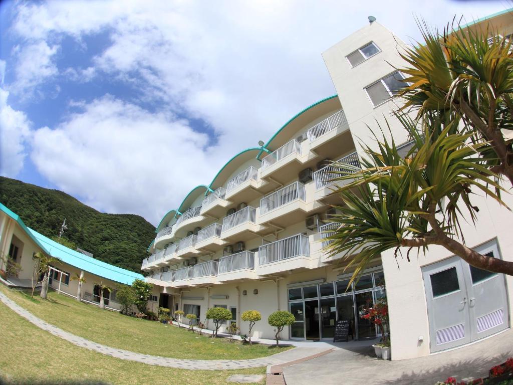 a building with a palm tree in front of it at Tokashiku Marine Villege in Tokashiki
