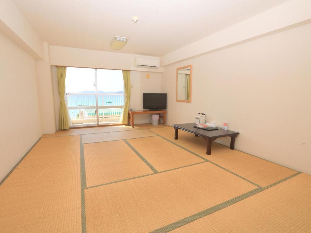 an empty room with a table and a television at Tokashiku Marine Villege in Tokashiki