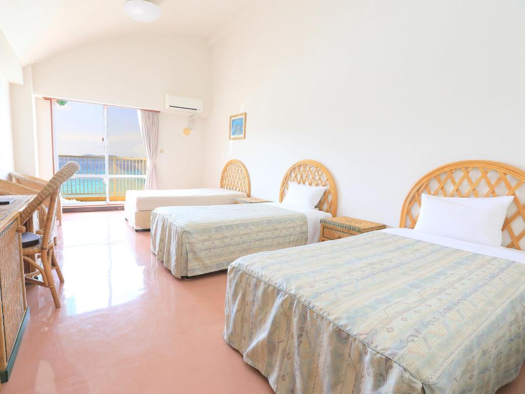 a hotel room with two beds and a balcony at Tokashiku Marine Villege in Tokashiki