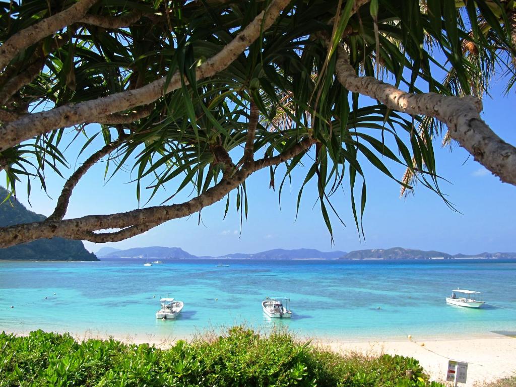 three boats in the water on a beach at Tokashiku Marine Villege in Tokashiki