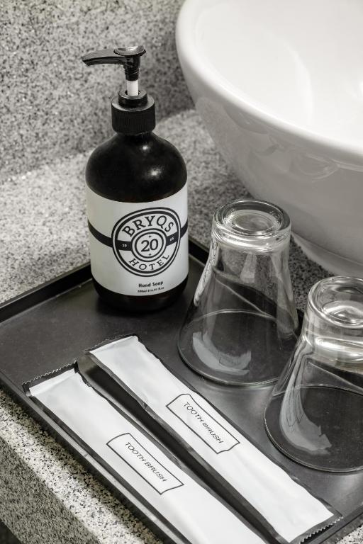 a bottle of soap and two glasses on a counter at BRYQS Hotel KL Sentral in Kuala Lumpur