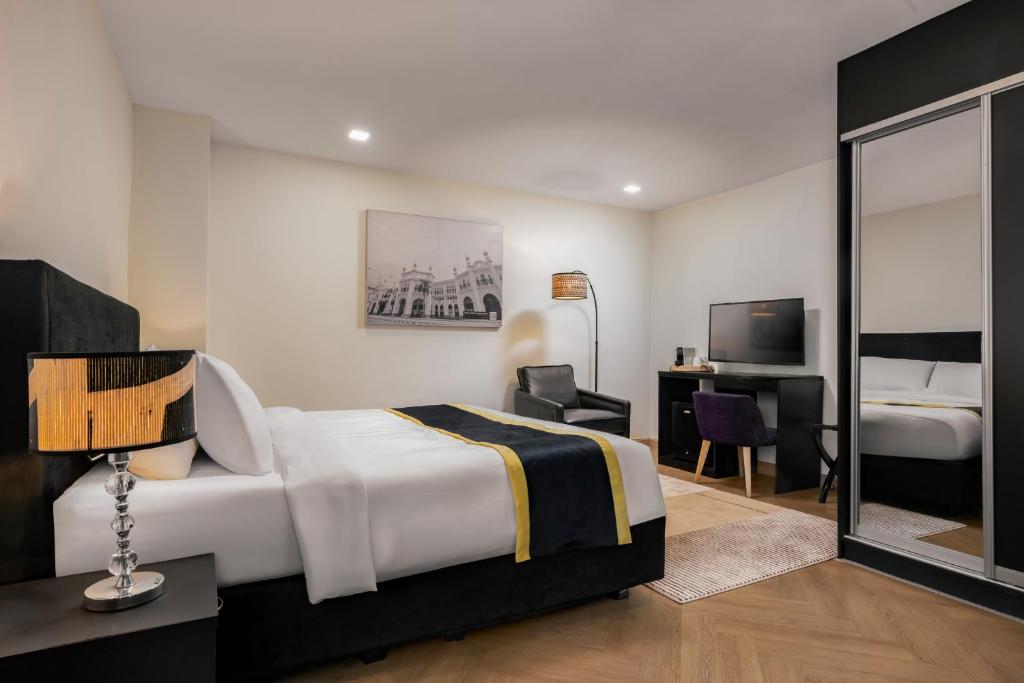 a bedroom with a bed and a desk and a television at BRYQS Hotel KL Sentral in Kuala Lumpur