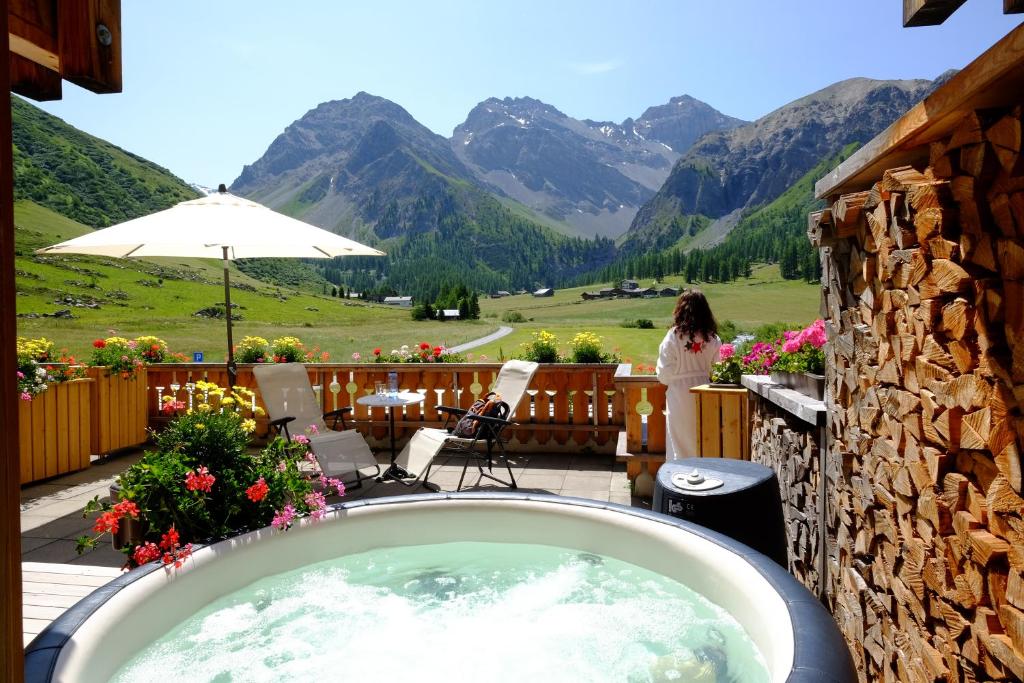 a woman standing on a deck with a bath tub at Walserhuus Sertig in Sertig Döfli