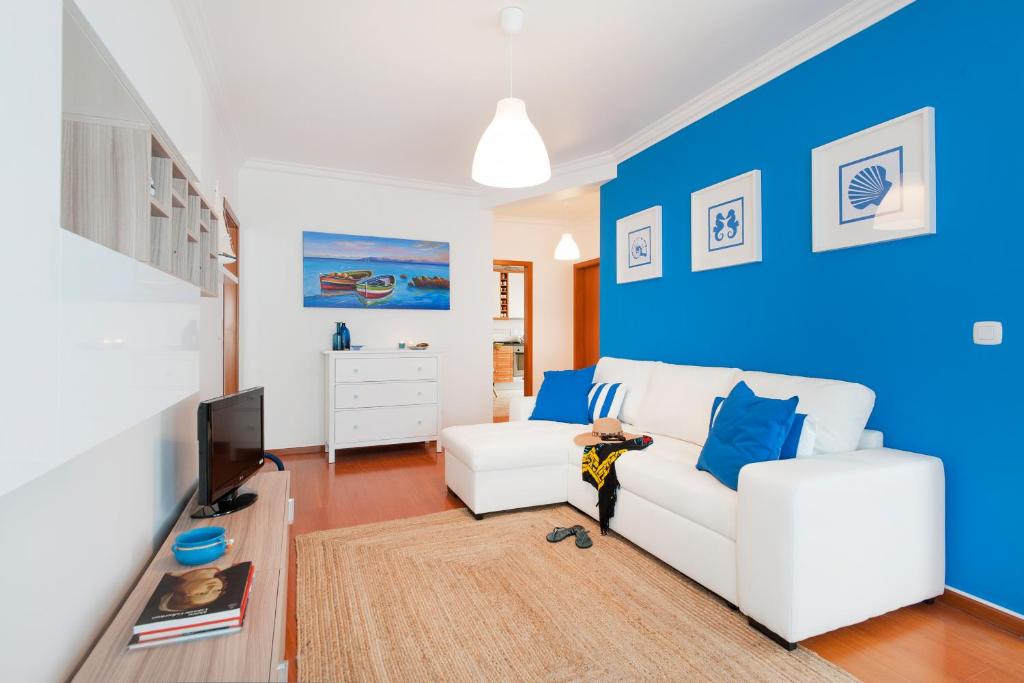 a living room with a white couch and a blue wall at Ericeira Apartment - Blue Sea in Ericeira