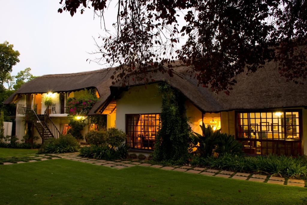 Cette grande maison est dotée d'un toit de chaume. dans l'établissement De Witt'e Guest House, à Bloemfontein