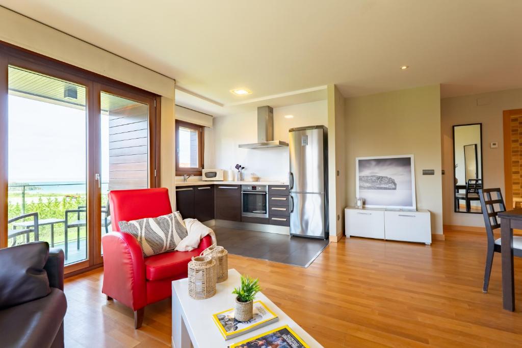 a living room with a red chair and a kitchen at Miracielos in Barro de Llanes