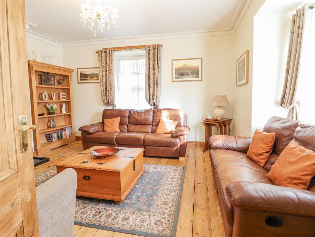 a living room with leather couches and a coffee table at Mor Iwerddon in Barmouth