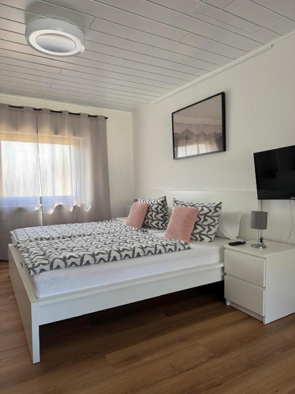 a white bedroom with a large bed and a television at Ferienhaus Lenartz in Kliding