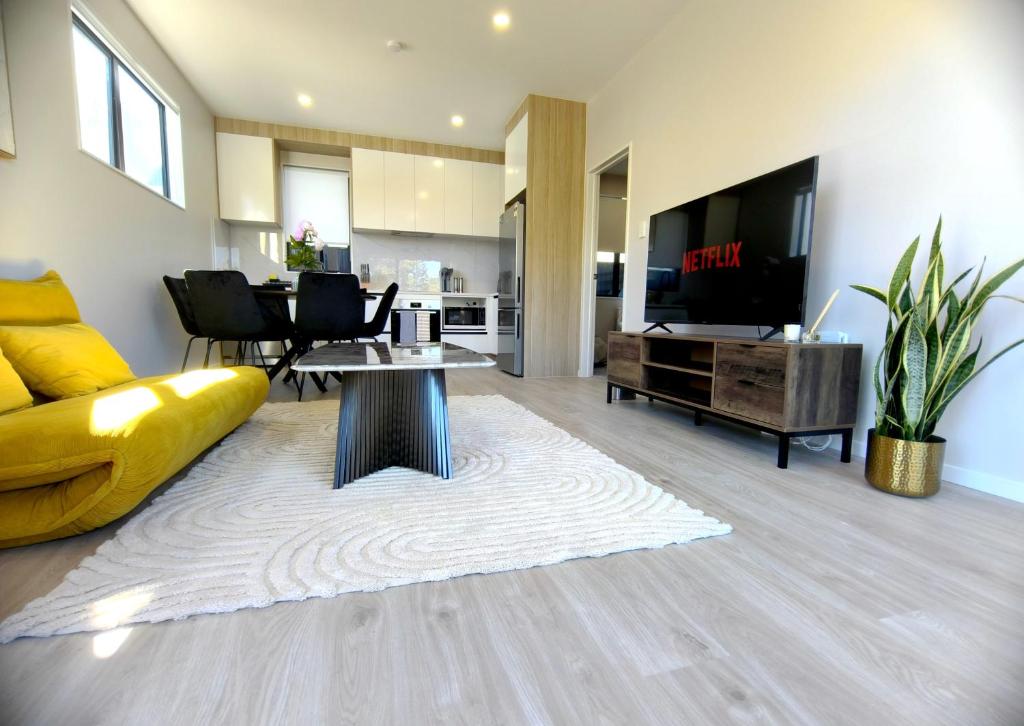 a living room with a yellow couch and a tv at Stylish 4BR Home, Netflix, Walk to Eateries and Schools in Auckland