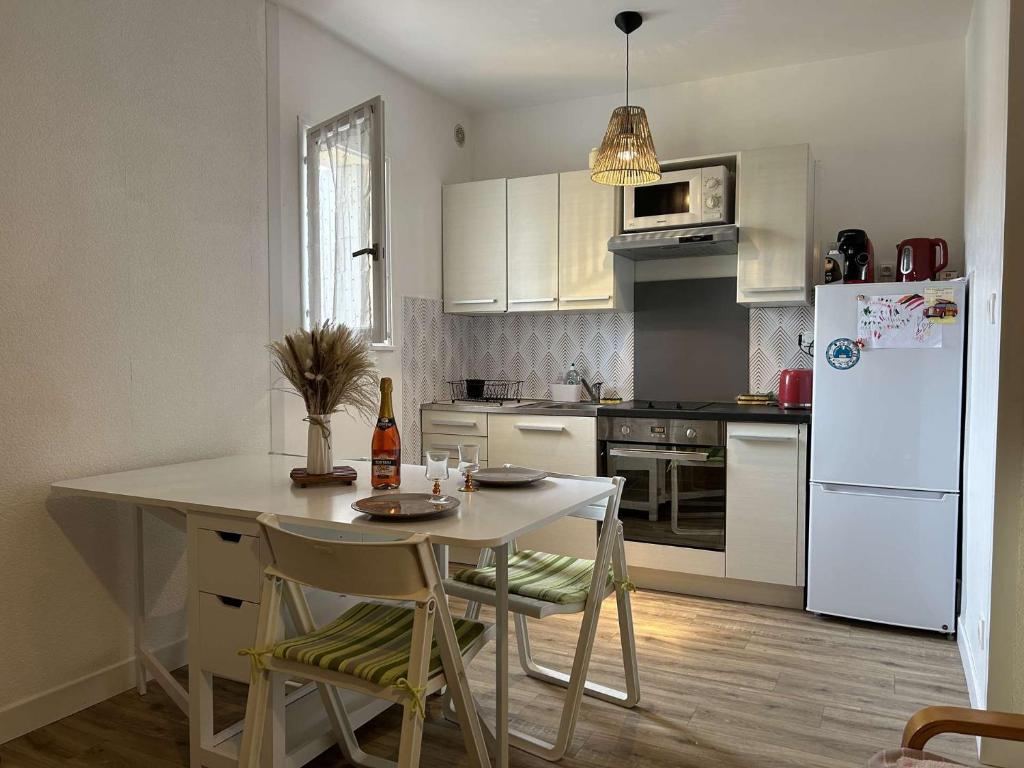 une cuisine avec une table et un réfrigérateur blanc dans l'établissement SP410-016 Appartement 3 pièces 6 couchages SAINT PIERRE LA MER, à Saint Pierre La Mer
