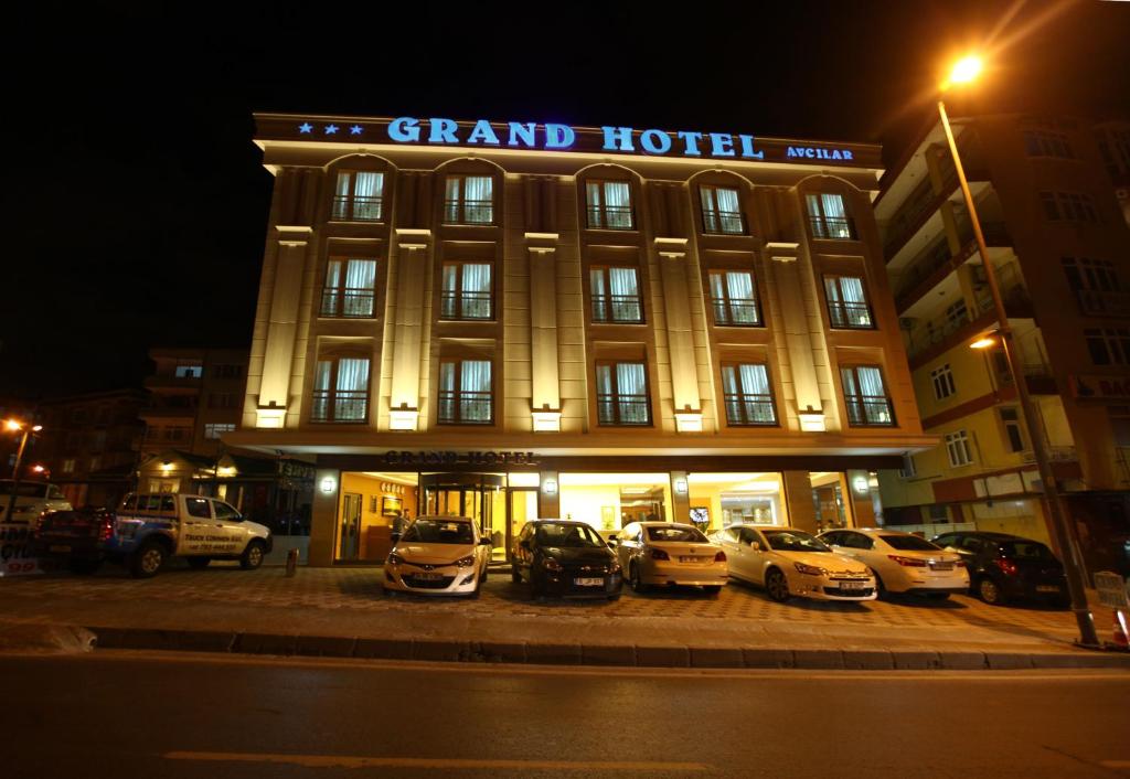 Un gran hotel con coches aparcados delante de él en Grand Hotel Avcilar, en Estambul