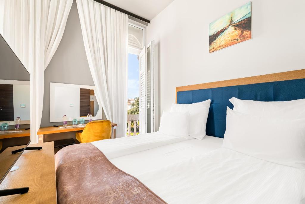 a bedroom with a bed and a desk and a window at Hotel Dua Residence in Poreč