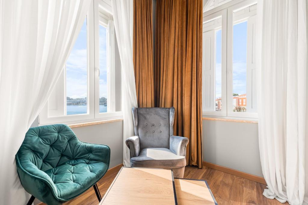 a living room with a chair and a table and window at Hotel Dua Residence in Poreč
