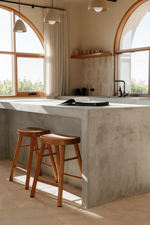 a kitchen with a large concrete counter with two stools at Stone - Rare Earth Retreats in McLaren Vale