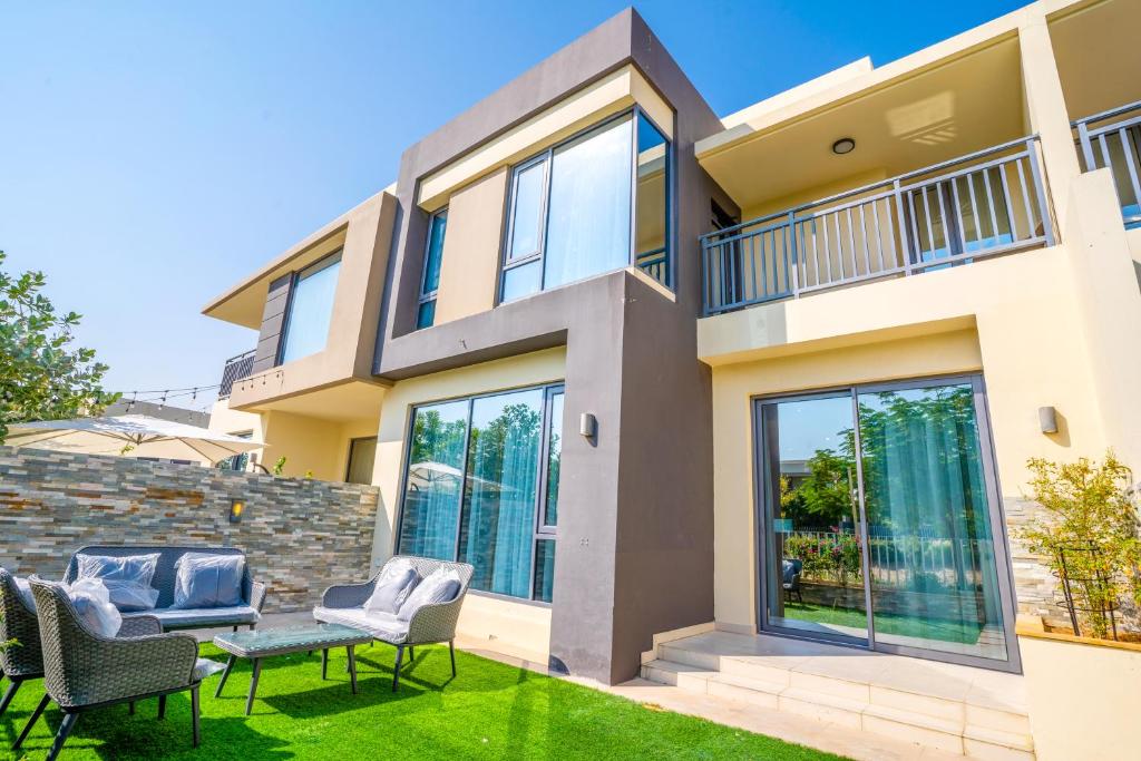 a house with chairs and a table in the yard at NewArabian Dubai HillsMaple Villa in Dubai